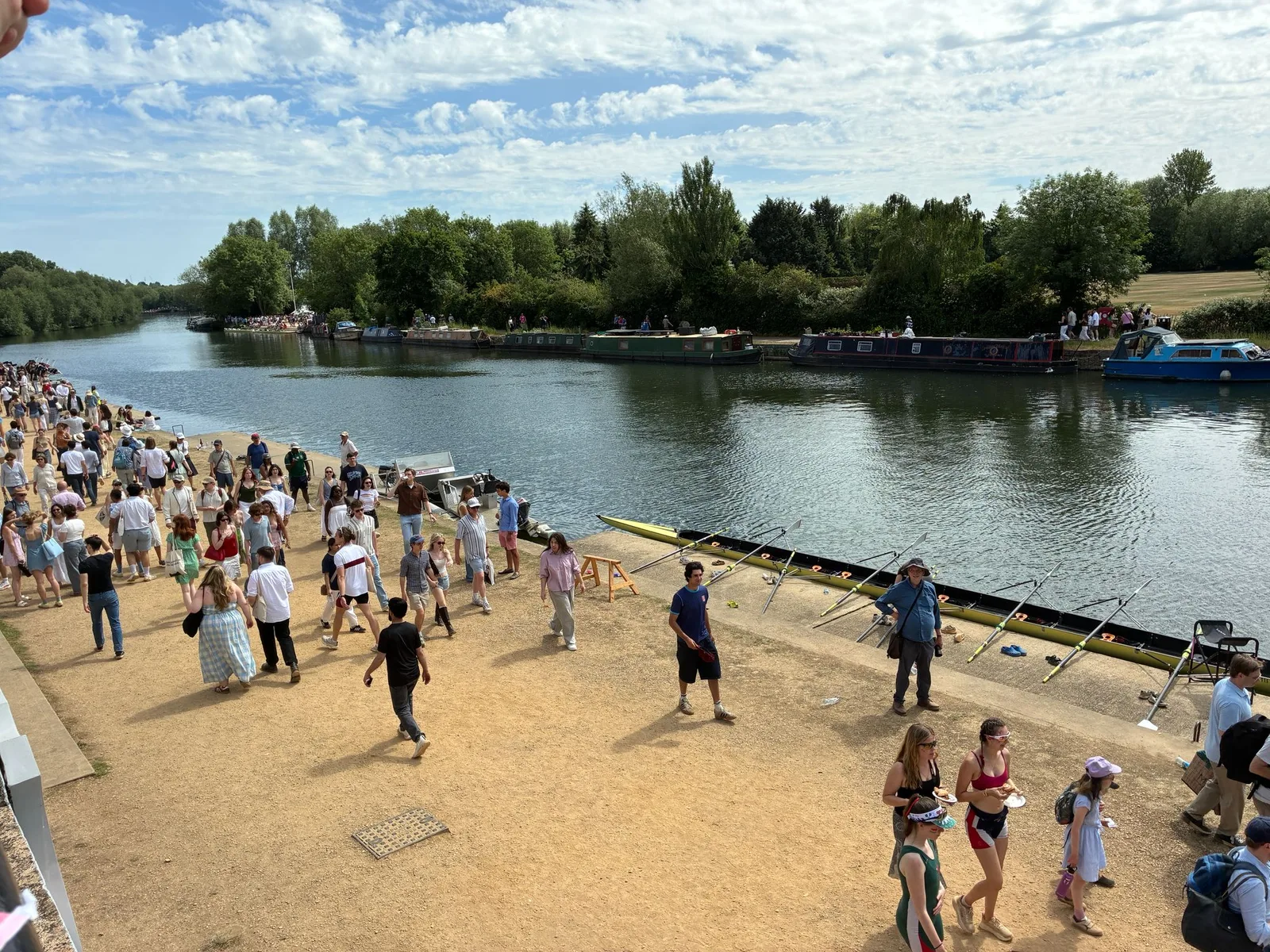 Crowds on the Isis towpath beside moored college barges during Summer Eights 2026 in Oxford