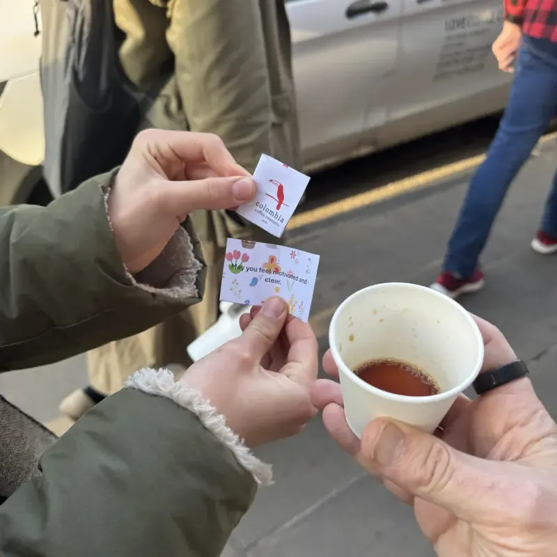 Hands holding a coffee cup with a small printed fortune card reading 'May you feel motivated and clear', May Morning 2026