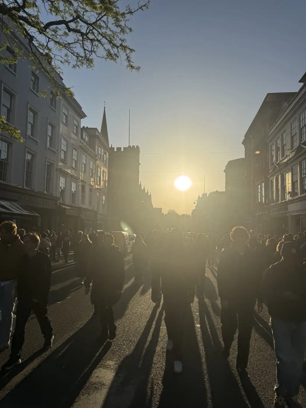 Crowd silhouettes on the High Street at sunrise as the choir finishes singing — May Morning 2026