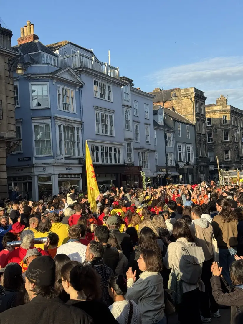 Sol Samba performers in red and yellow on Broad Street with yellow flag, May Morning 2026